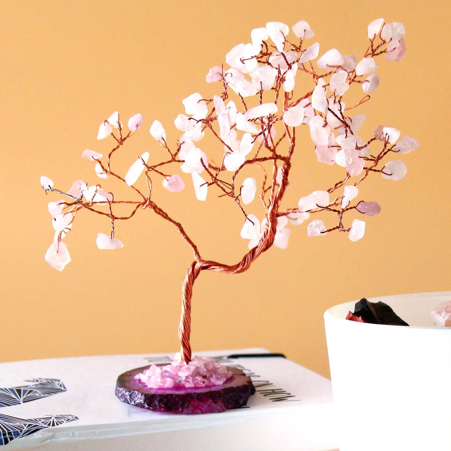 Decorative tree with pink blossoms on a book against a yellow background