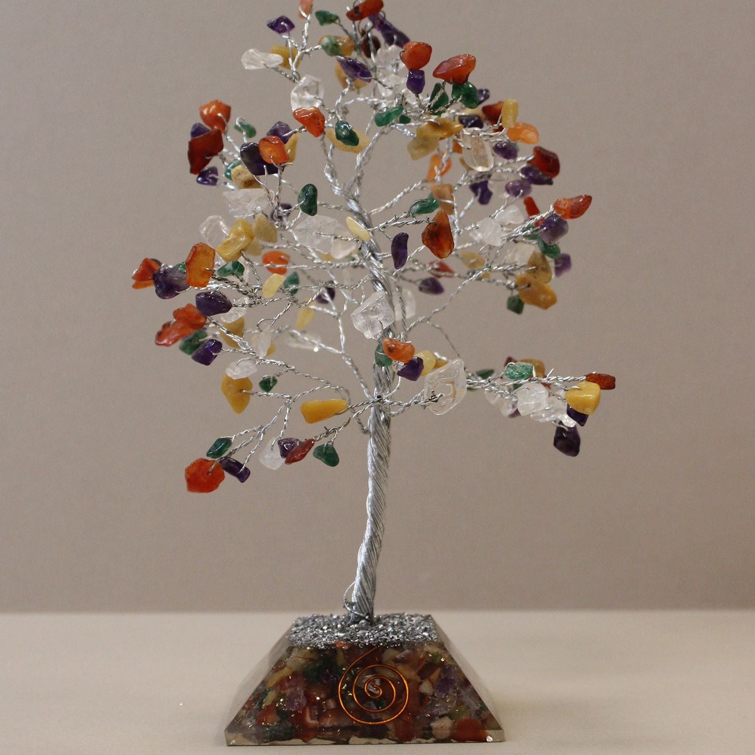 Decorative crystal tree with multicolored stones on a beige background