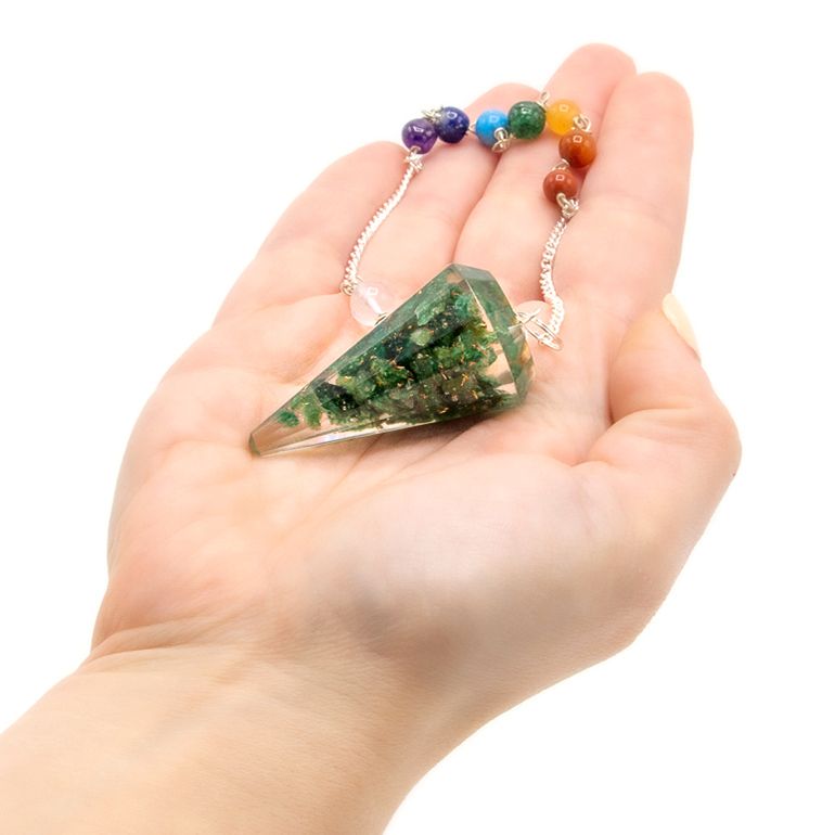 Hand holding a green crystal pendant with colorful beads on a white background