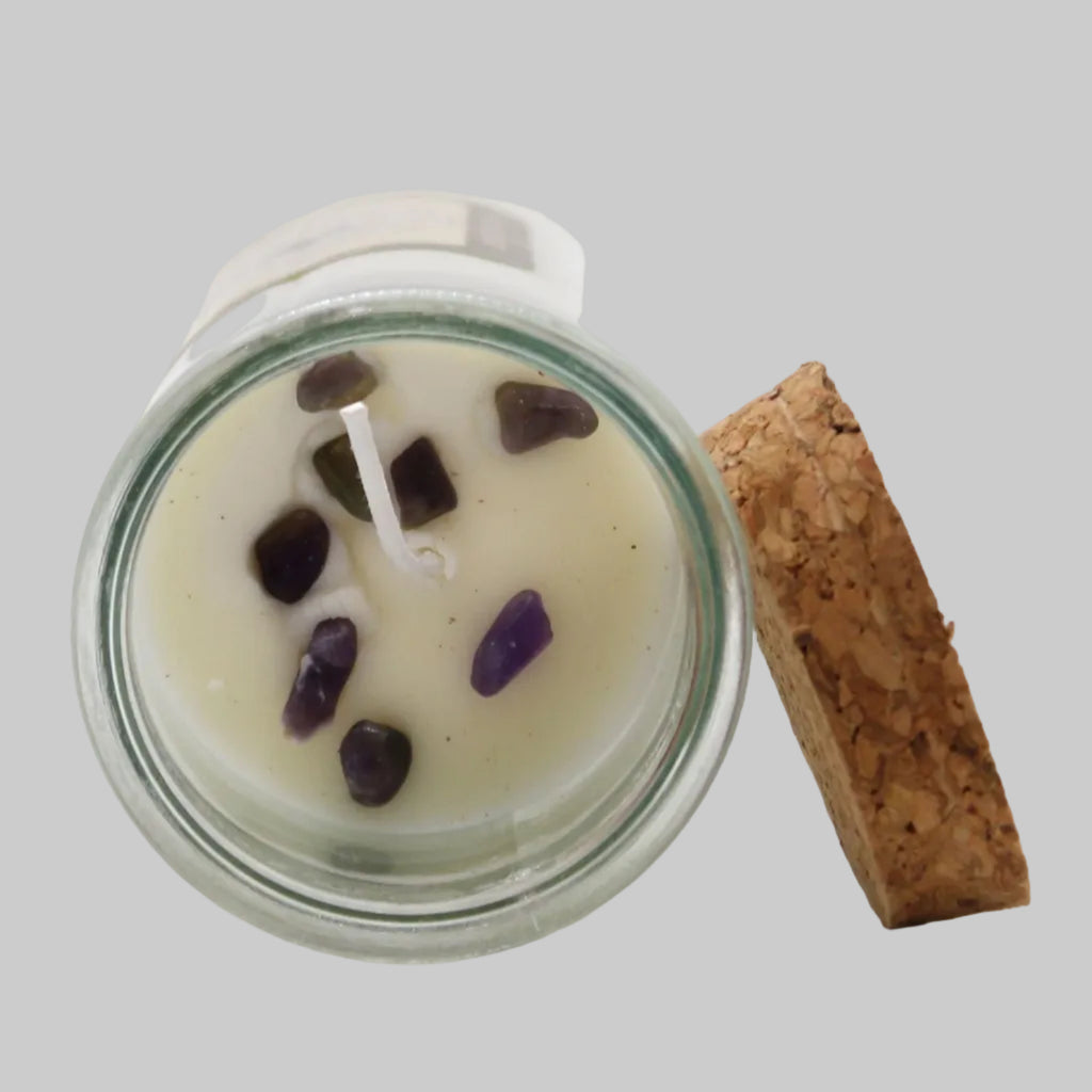 Candle in a glass jar with purple stones on a white background