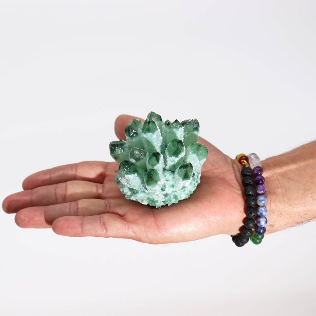 Hand holding a green crystal ball with a plain background