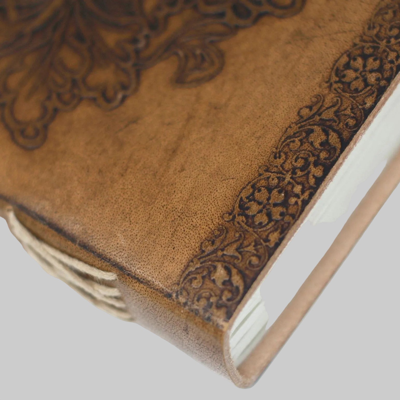 Close-up of a brown leather notebook with intricate embossed designs on a white background