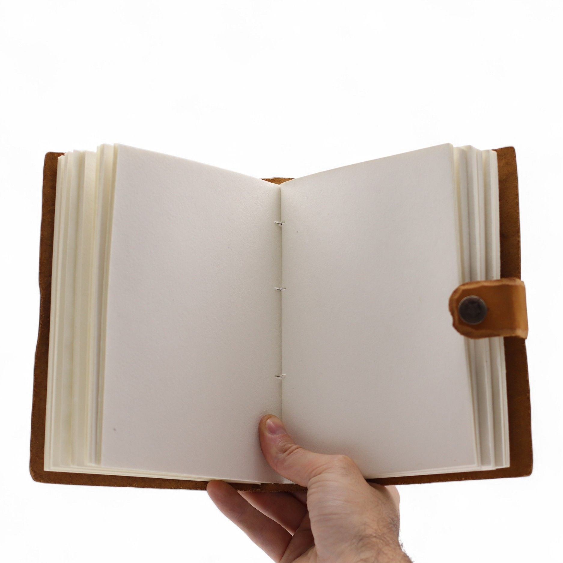 Hand holding an open notebook with a brown leather cover on a white background