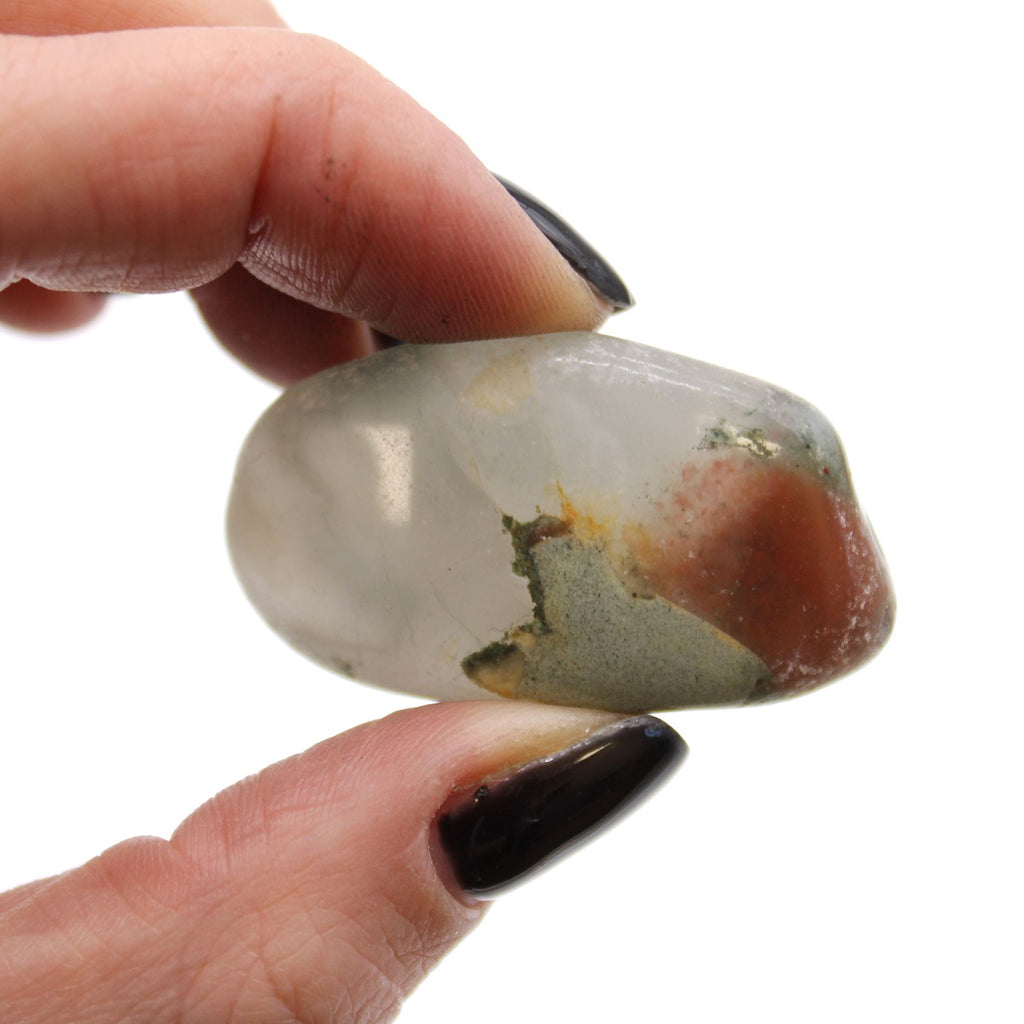 Hand holding a polished gemstone with a white background