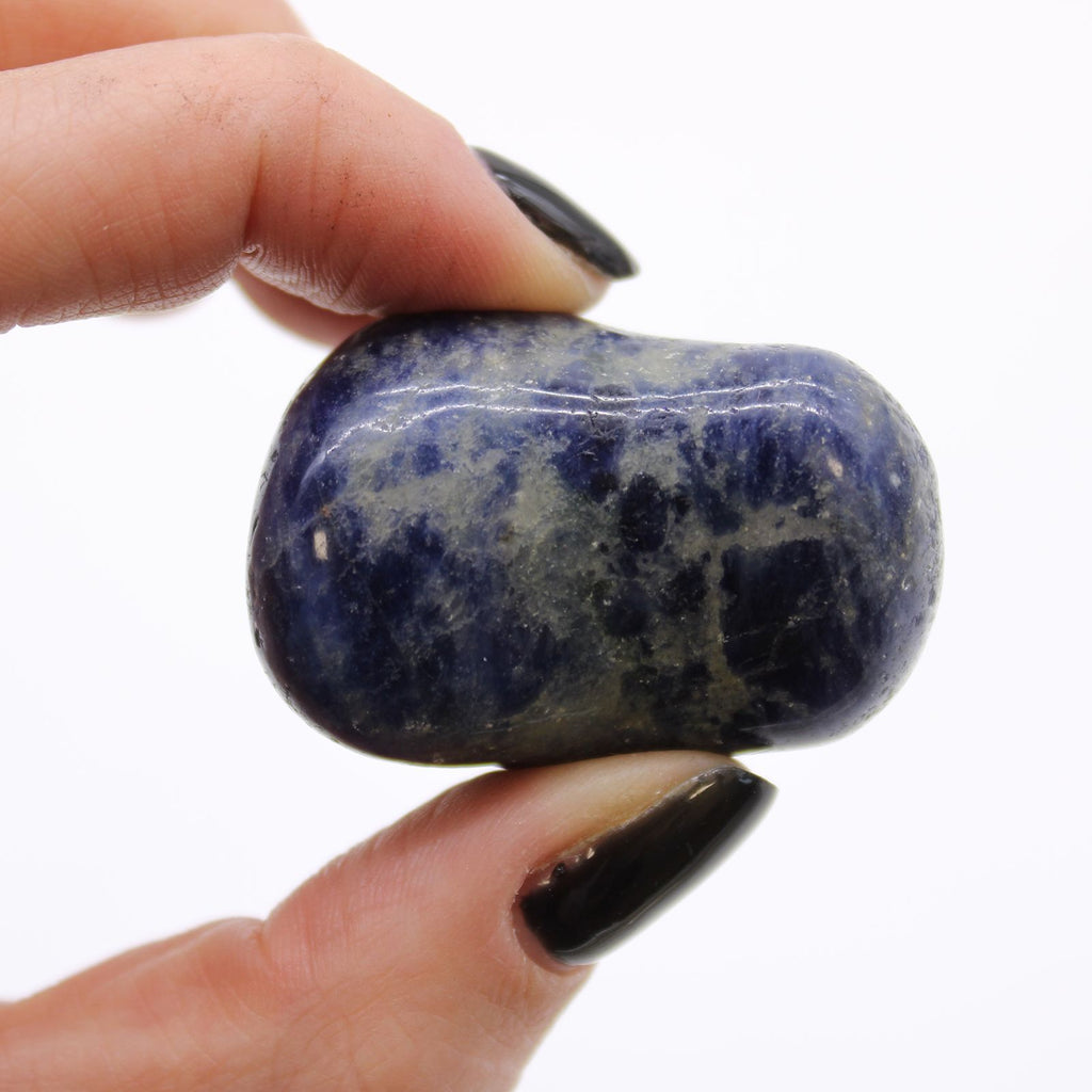 Hand holding a blue and white marbled stone against a white background