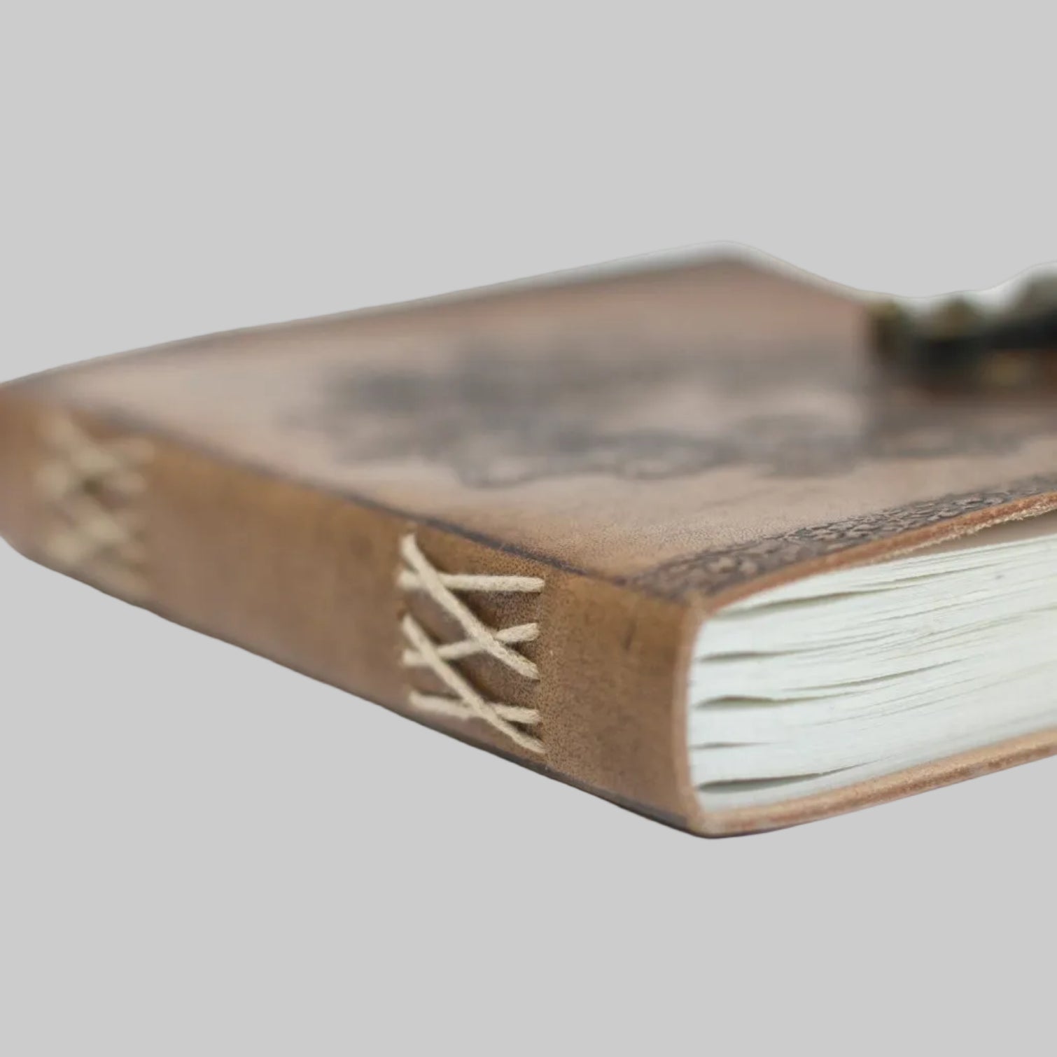 Close-up of a leather-bound notebook with white pages on a white background