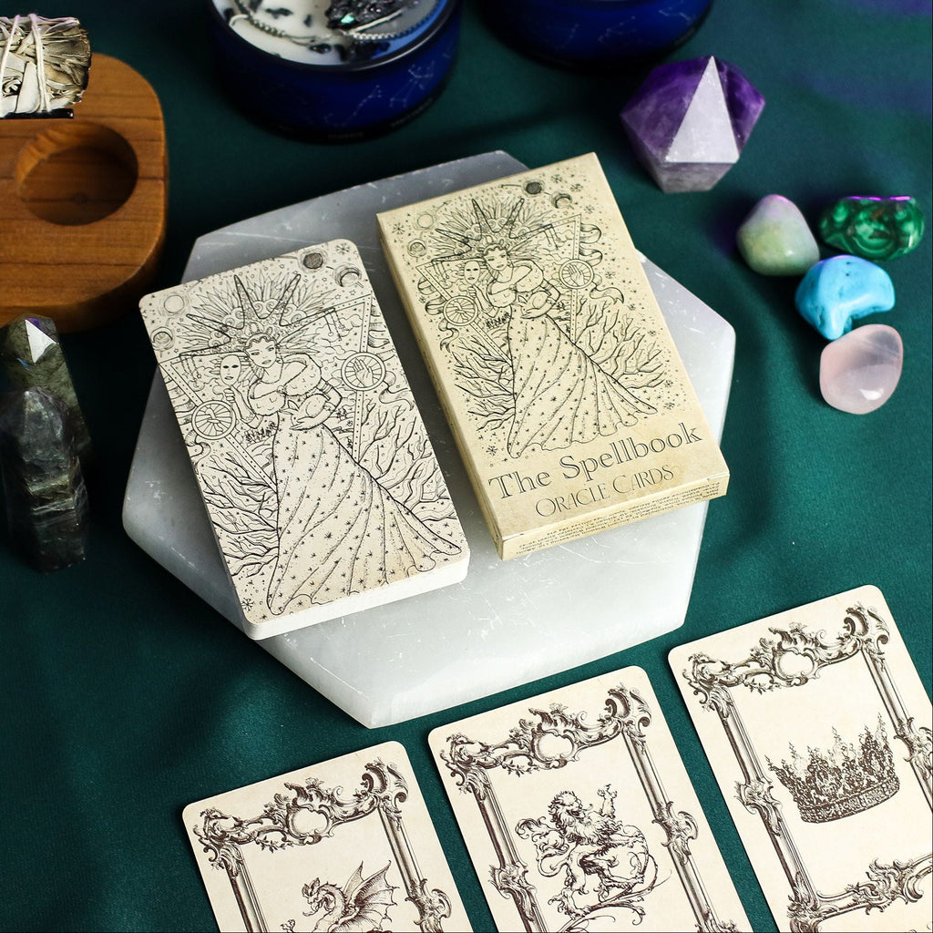 Witchcraft items including tarot cards, crystals, and a book titled 'The Spellbook' on a green surface.