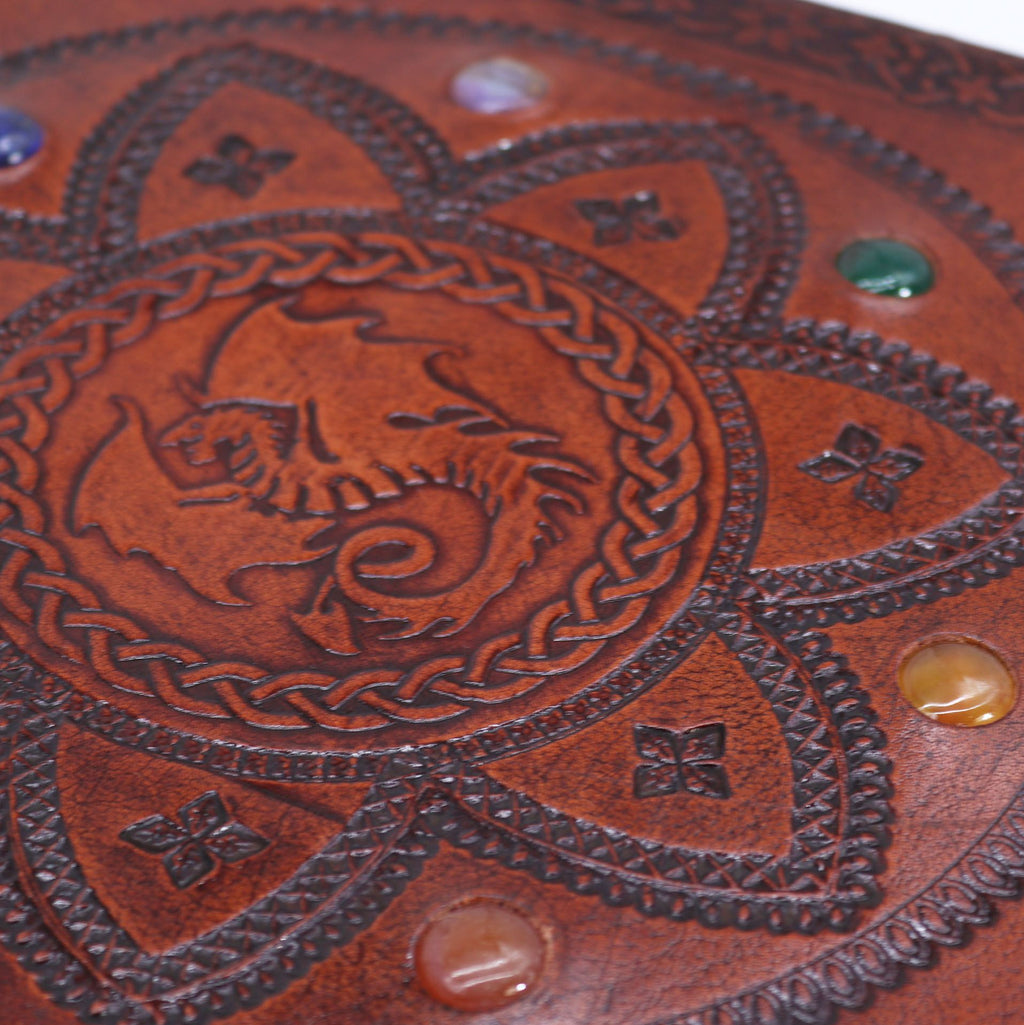 Close-up of a brown leather product with embossed dragon design and decorative elements.