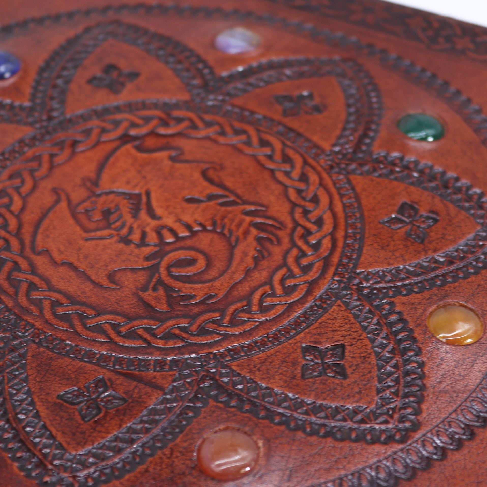 Close-up of a brown leather product with embossed dragon design and decorative elements.