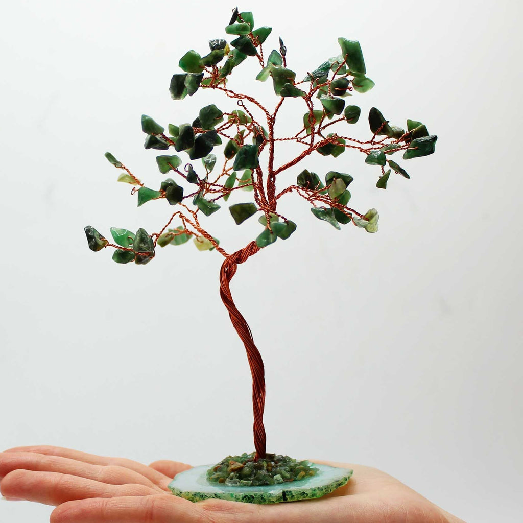 Small tree made of green stones on a hand with a white background
