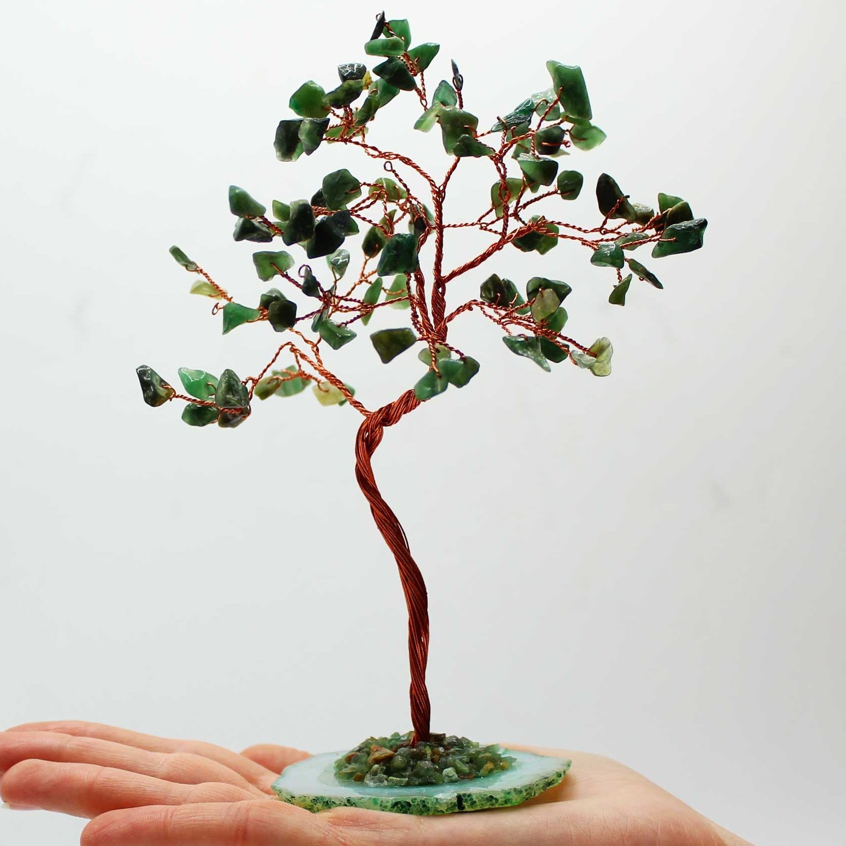 Small tree made of green stones on a hand with a white background