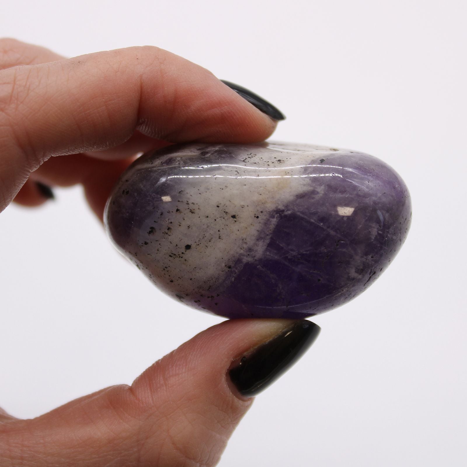 Hand holding a purple and white stone against a white background