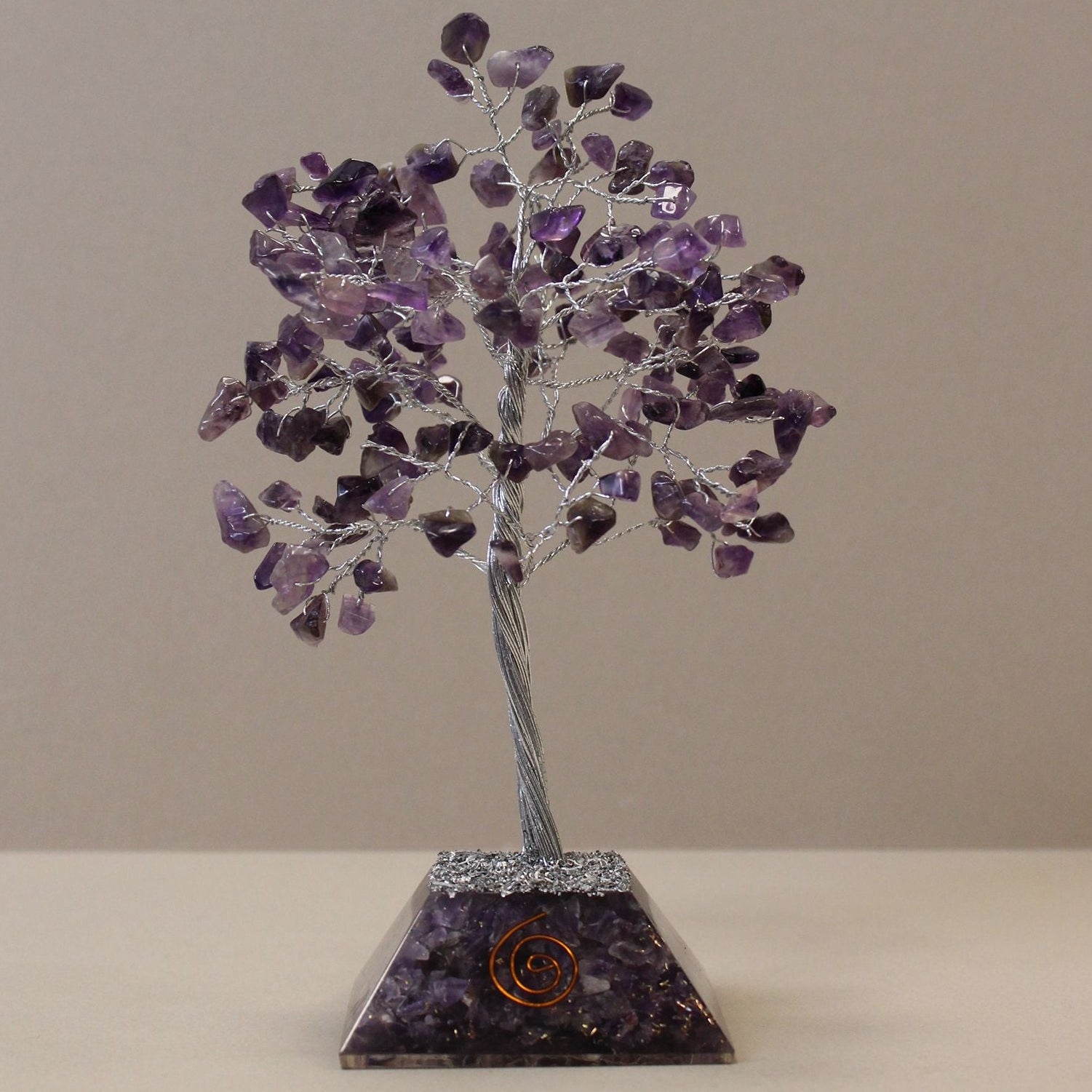 Crystal tree sculpture with purple stones on a beige background