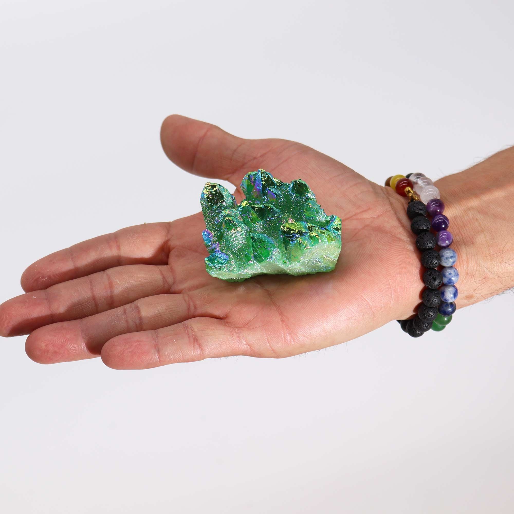 Hand holding a green crystal on a plain background