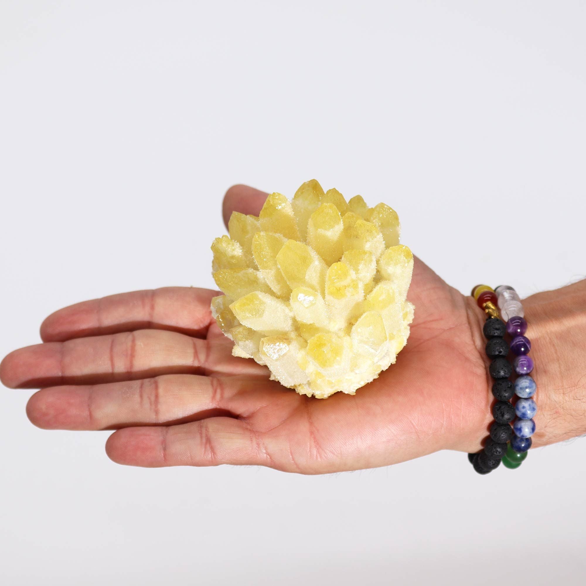 Hand holding a yellow crystal with a plain background