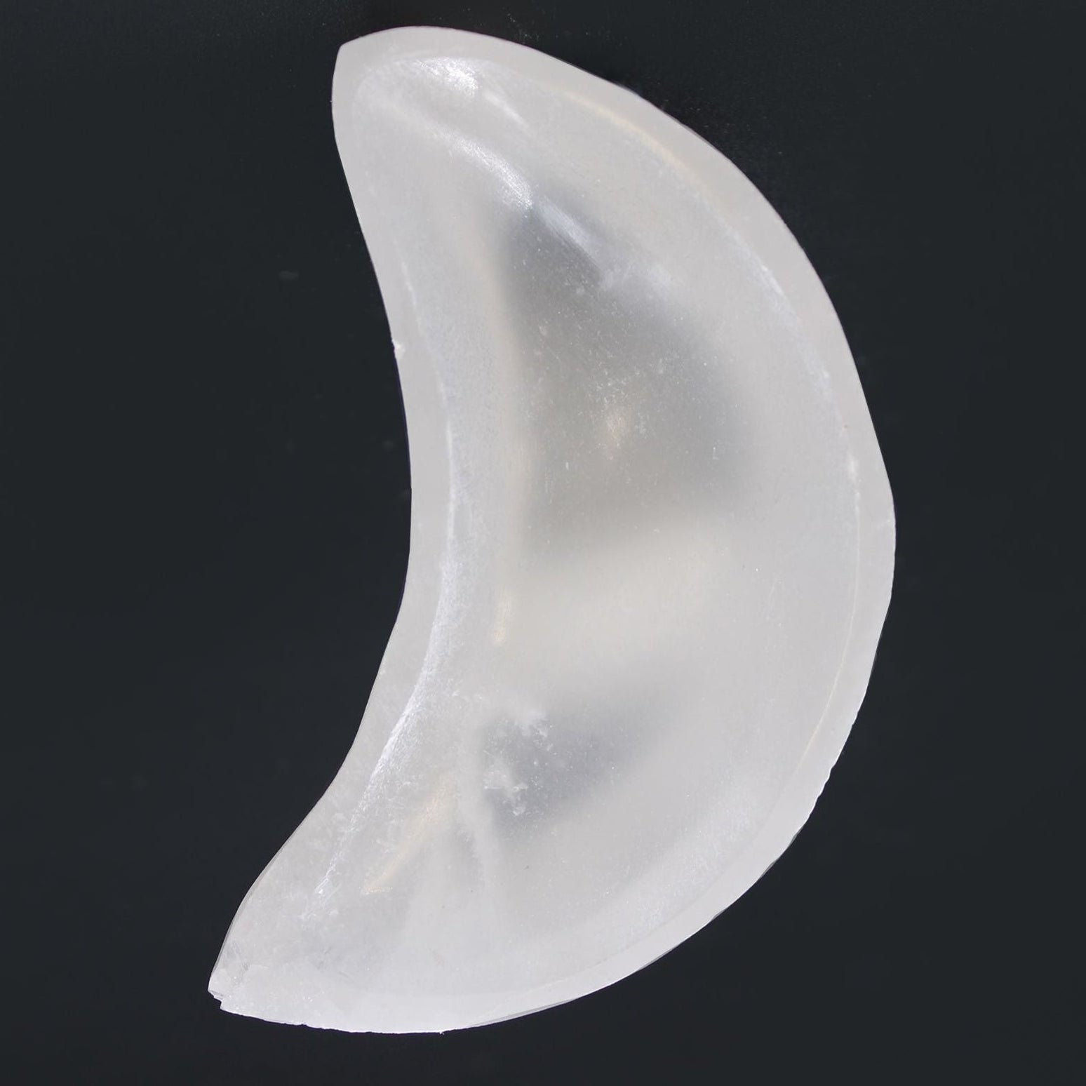 Clear silicone breast form on a black background