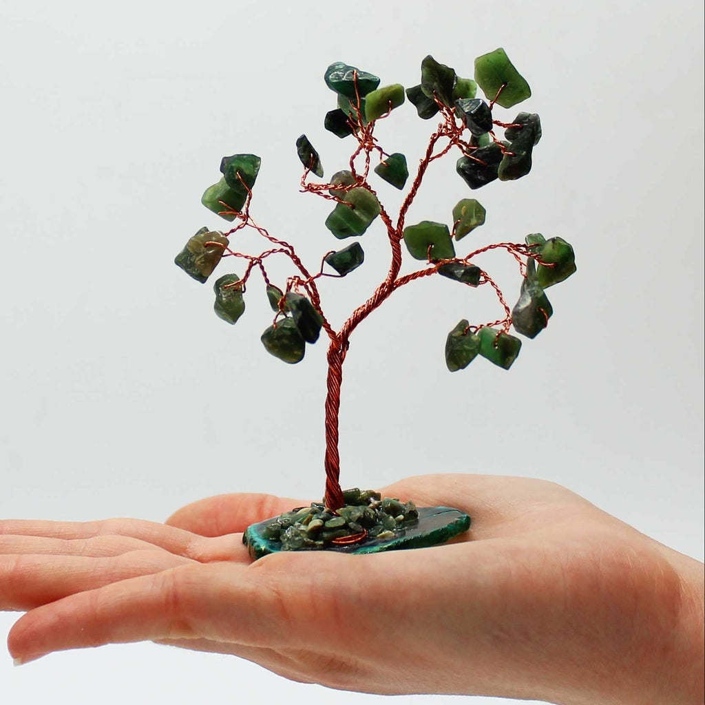 Small decorative tree with green stones held in a hand against a light background