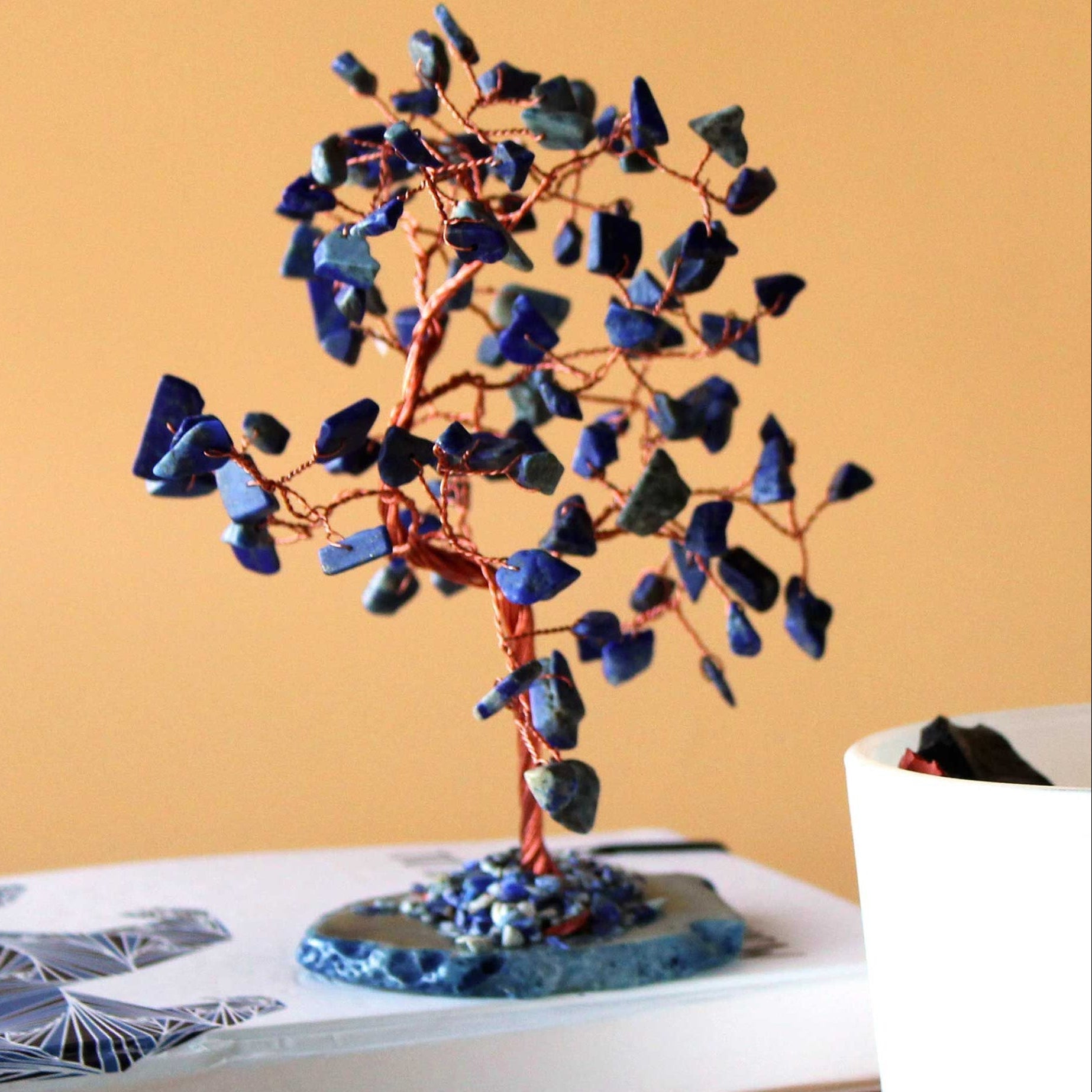 Decorative tree made of blue stones on a book with a plain background