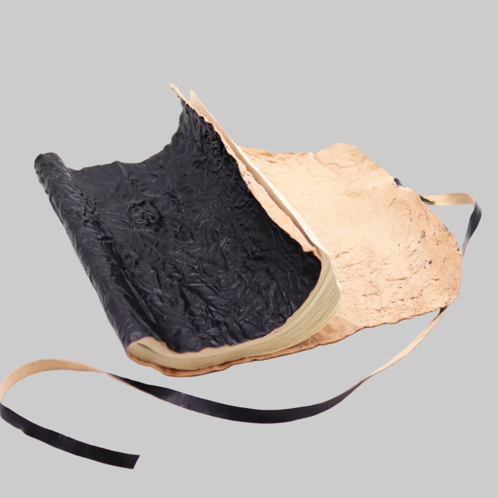 Textured black and beige bag with a strap on a white background