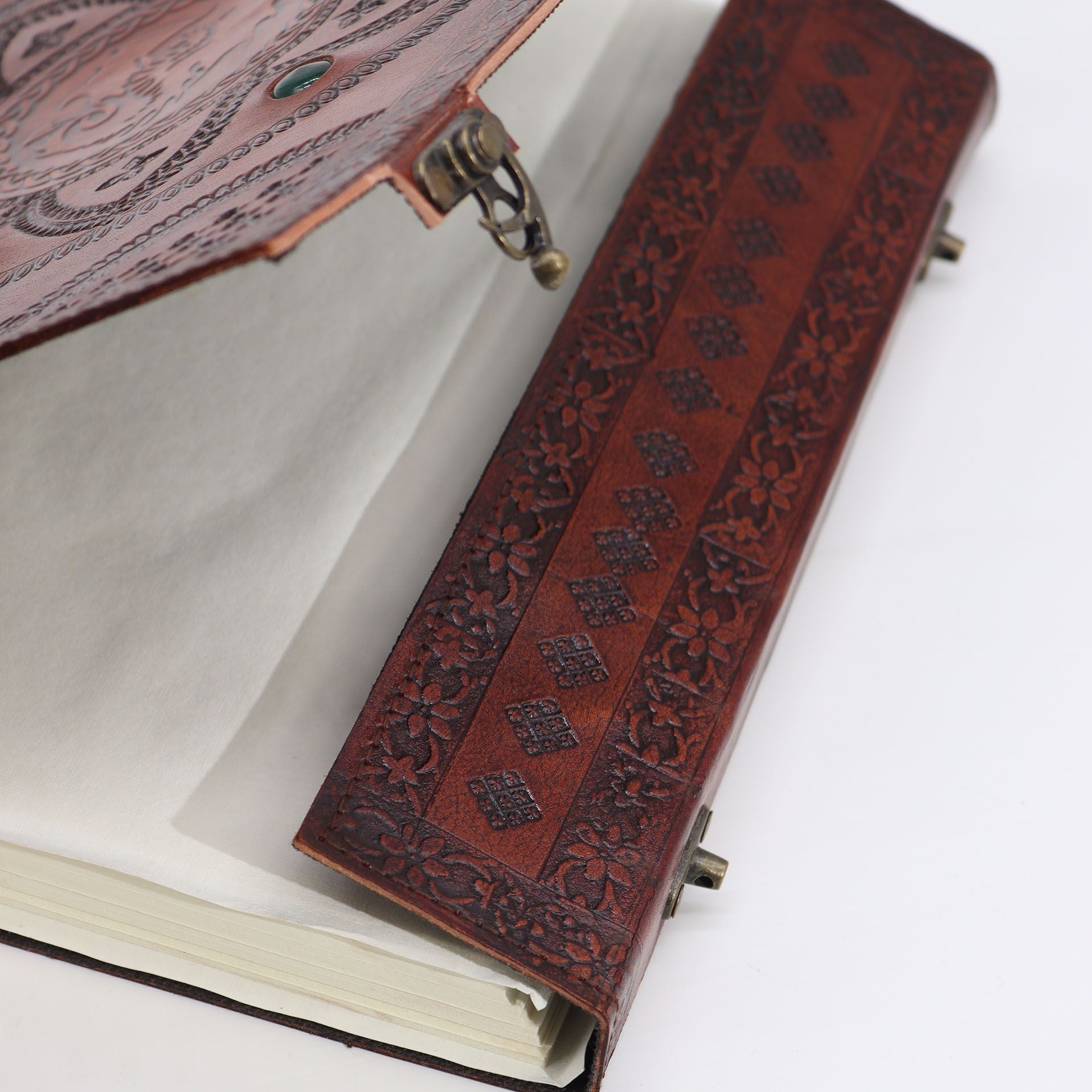 Close-up of a leather-bound book with intricate designs on a white background