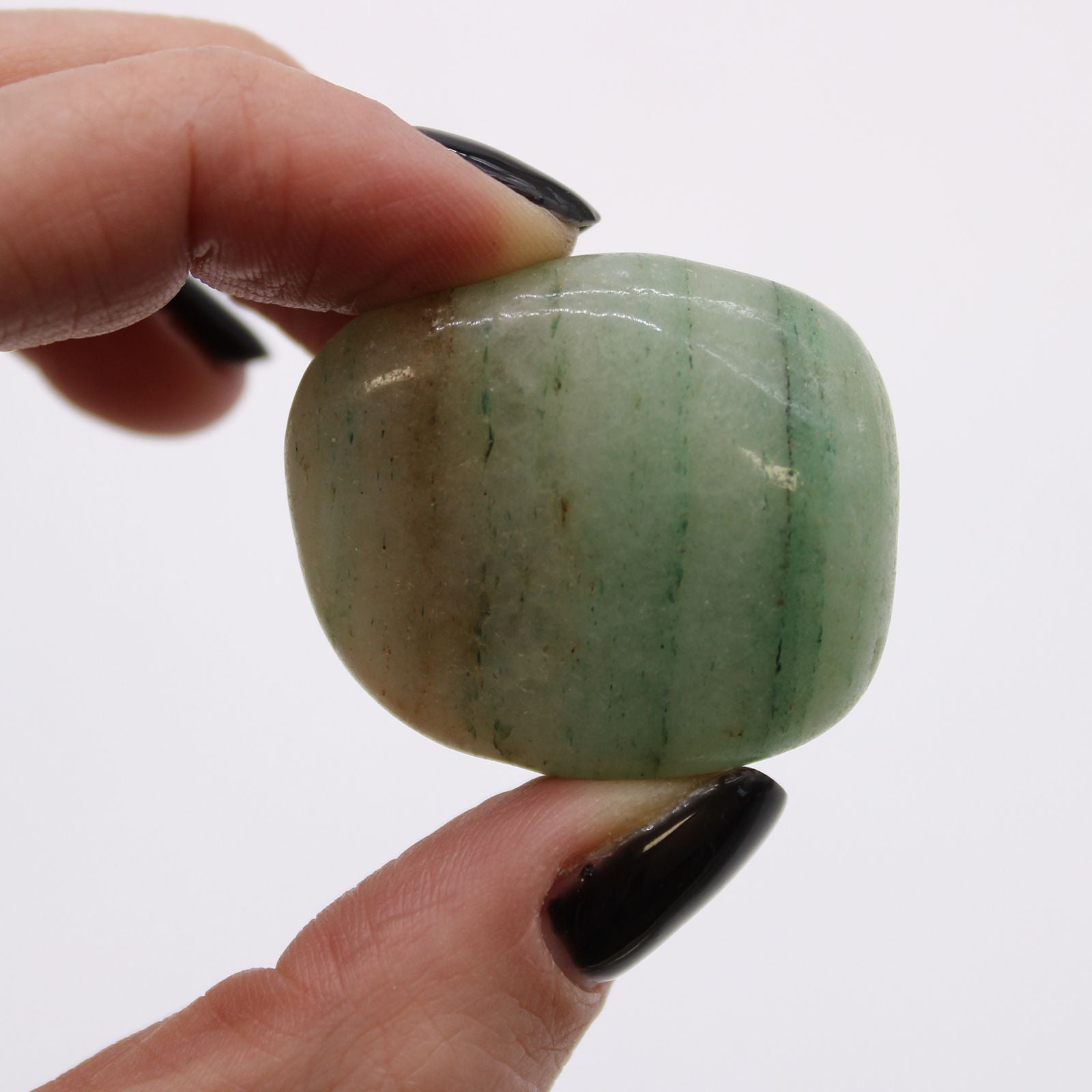 Hand holding a green stone against a white background
