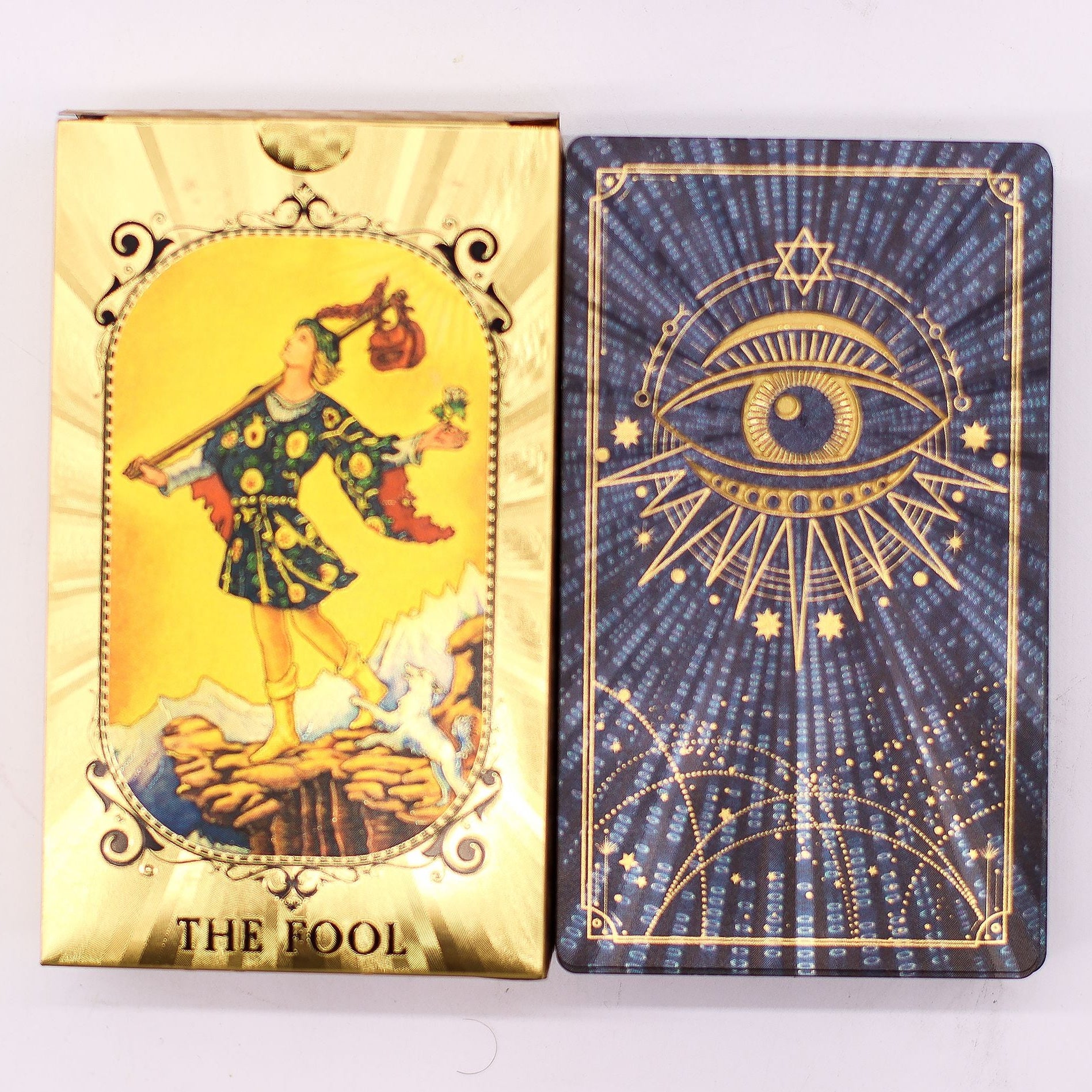 Two tarot cards, one gold and one blue, with intricate designs and text on a white background.