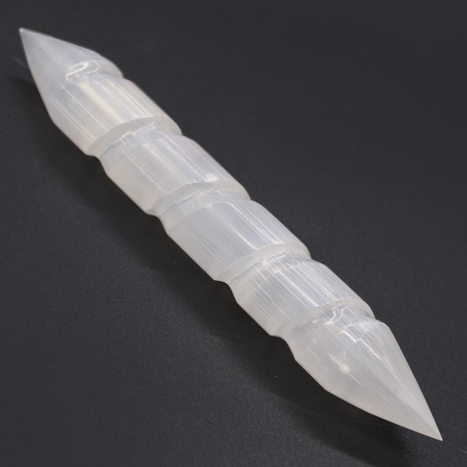Clear plastic tool with pointed ends on a black background