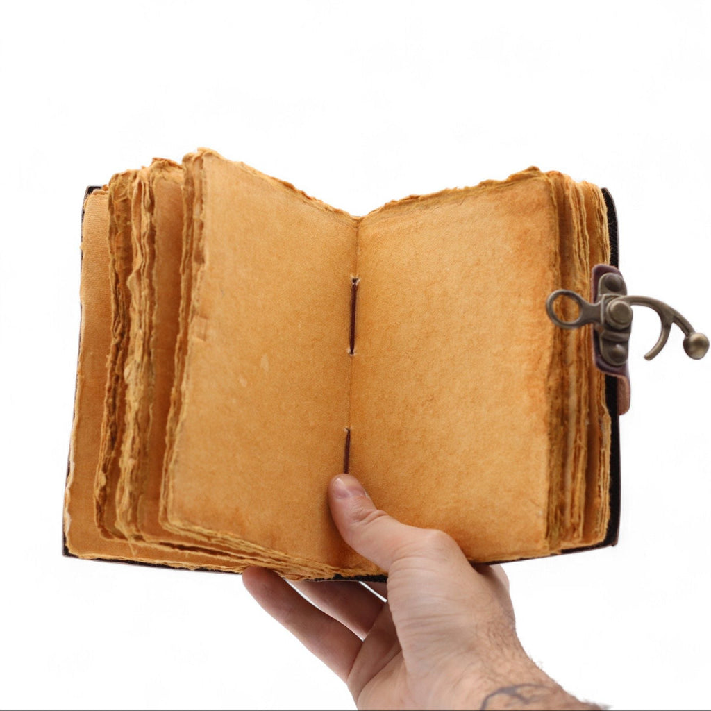 Hand holding an open vintage leather-bound book with a white background