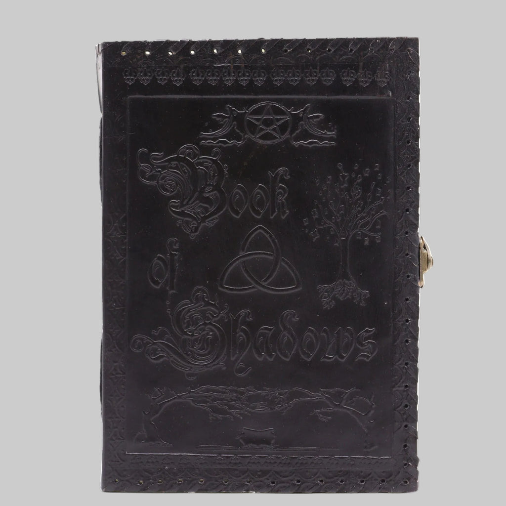 Black leather-bound book titled 'Book of Shadows' with embossed designs on a white background