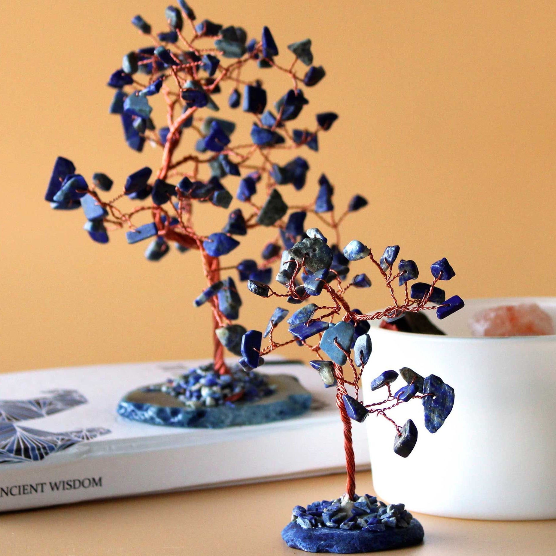 Decorative tree with blue stones on a wooden surface with a book in the background