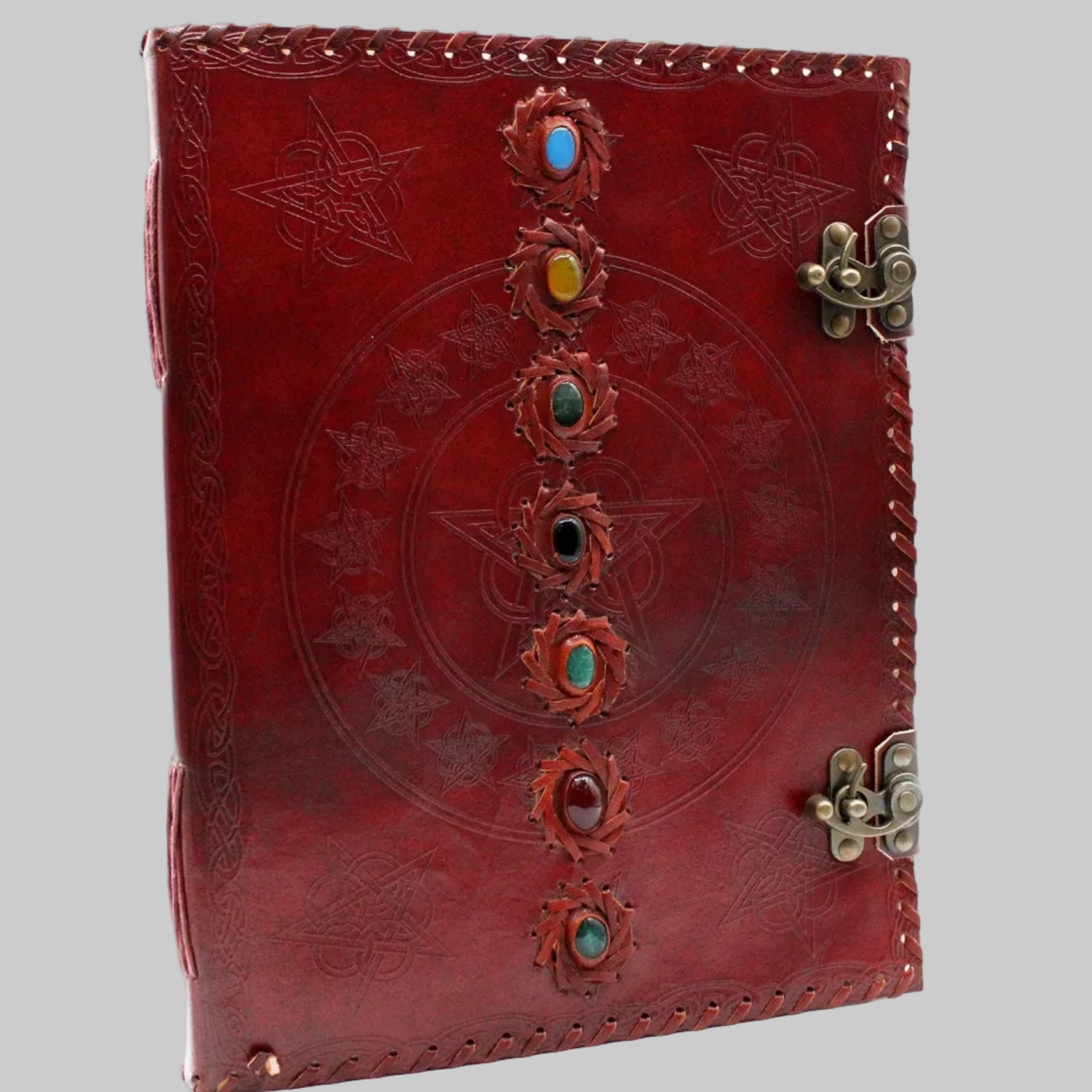 Red leather journal with embossed designs and colorful stones on a white background