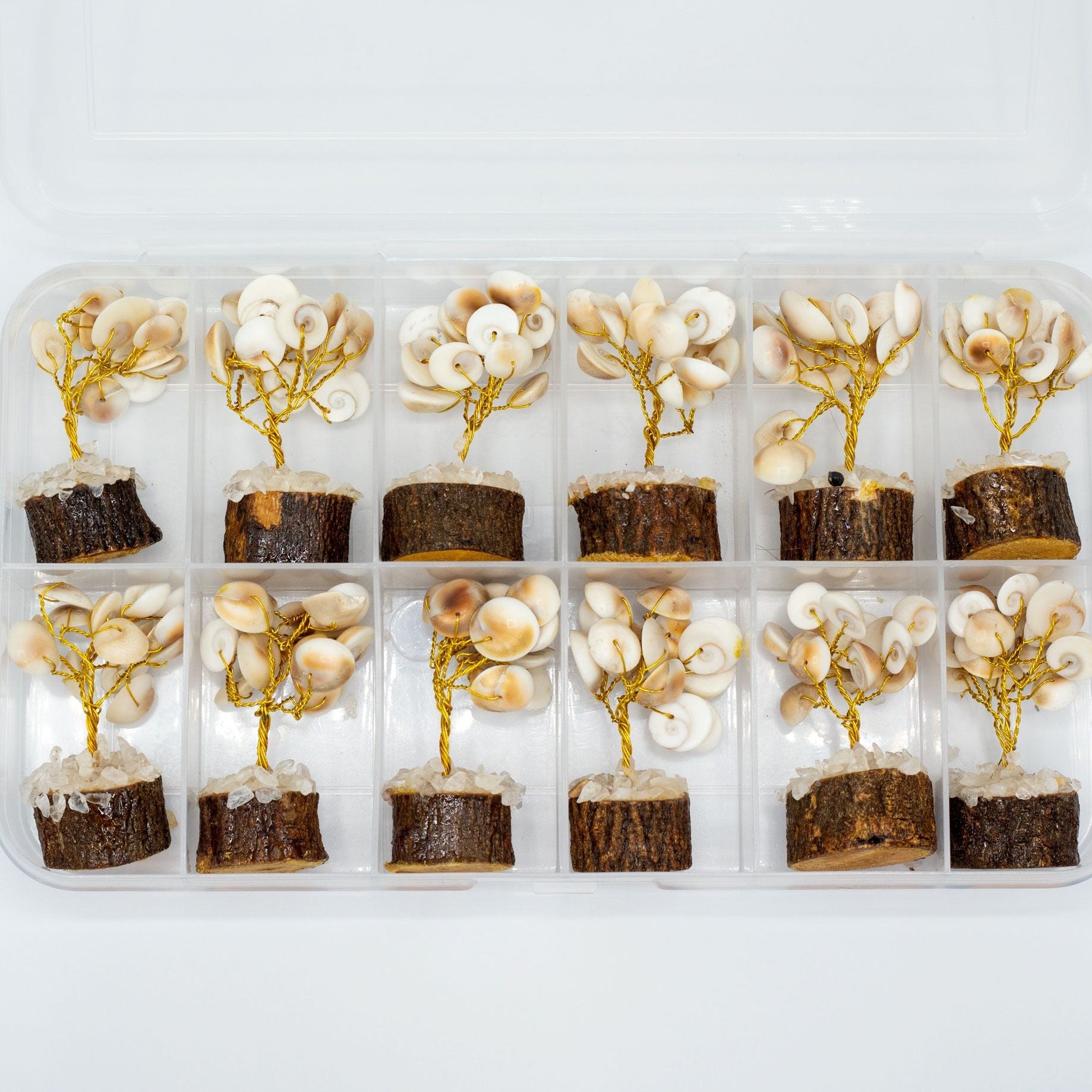 Small tree-shaped desserts with white and gold decorations in a clear plastic container on a white background