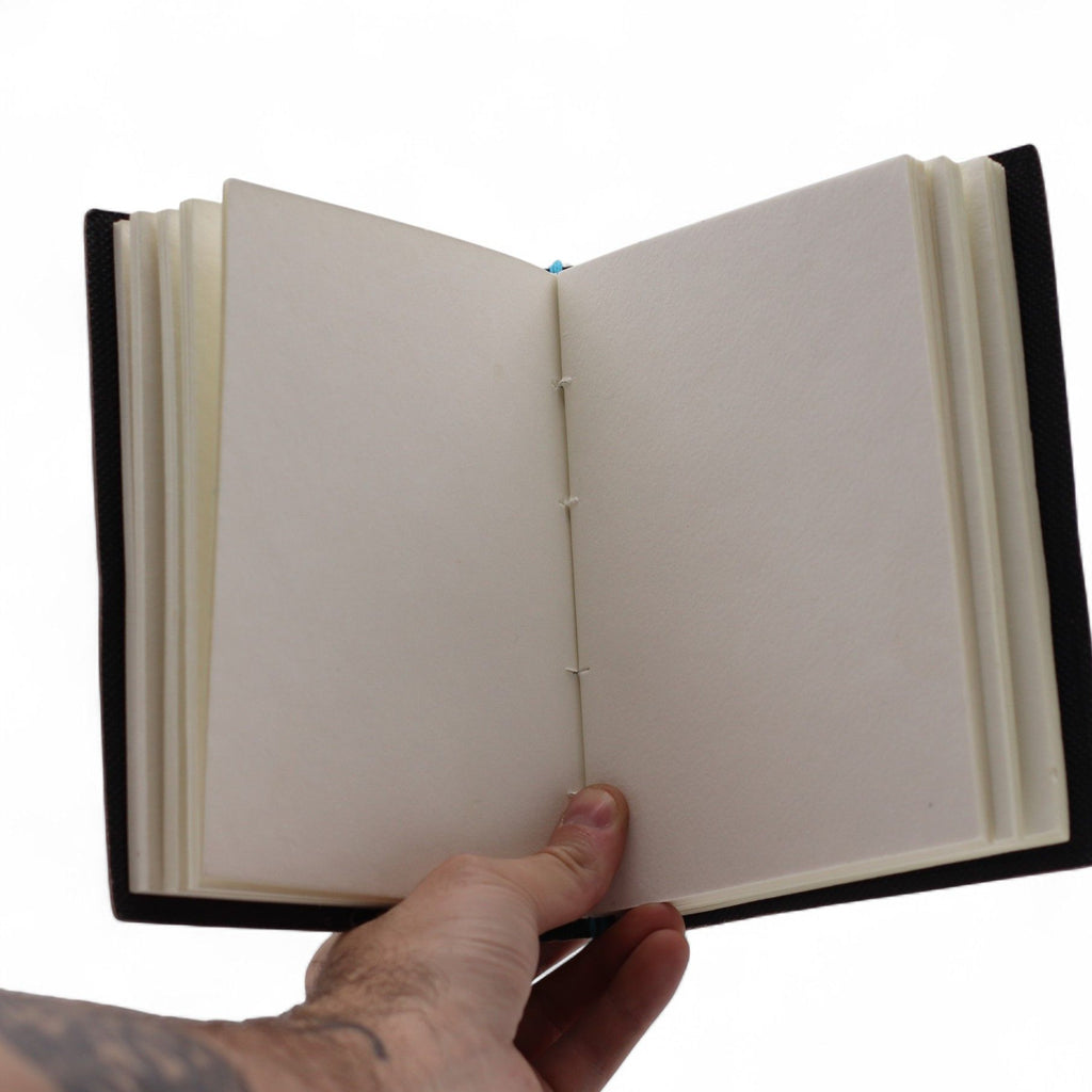 Hand holding an open notebook with a white background