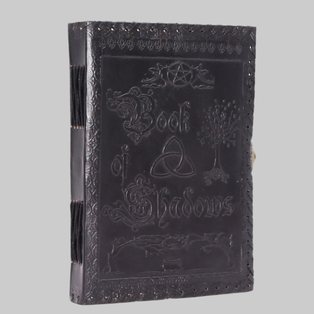 Black leather-bound book titled 'Book of Shadows' with embossed designs on a white background