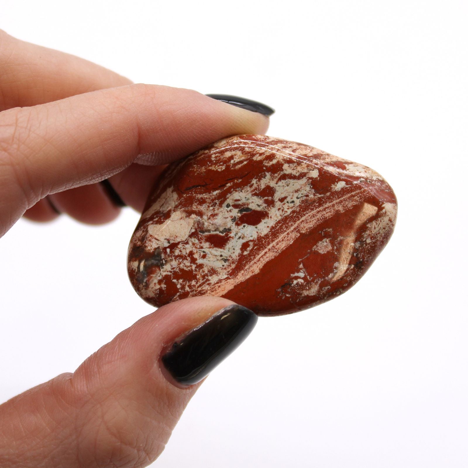 Hand holding a brown and white patterned stone against a white background