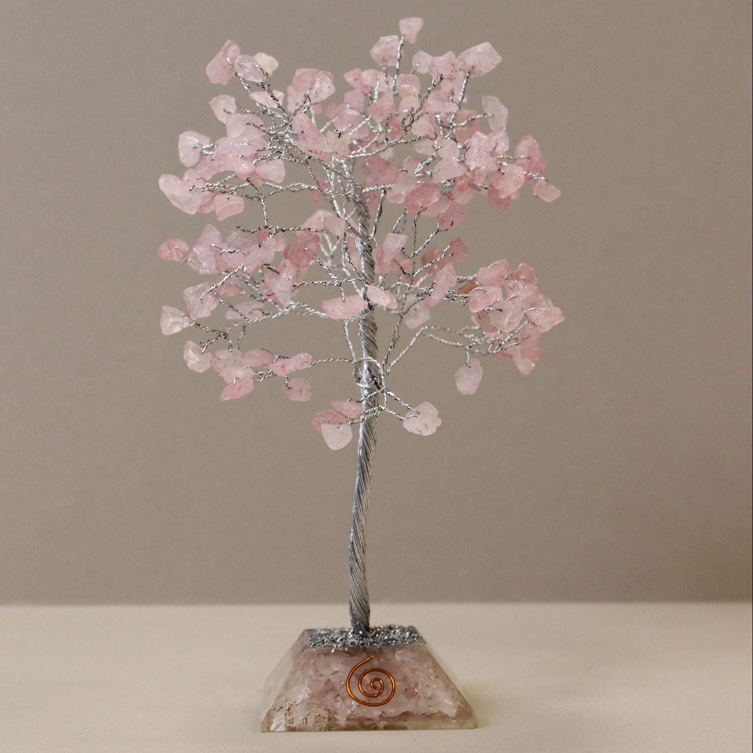 Decorative tree sculpture with pink stones on a beige background