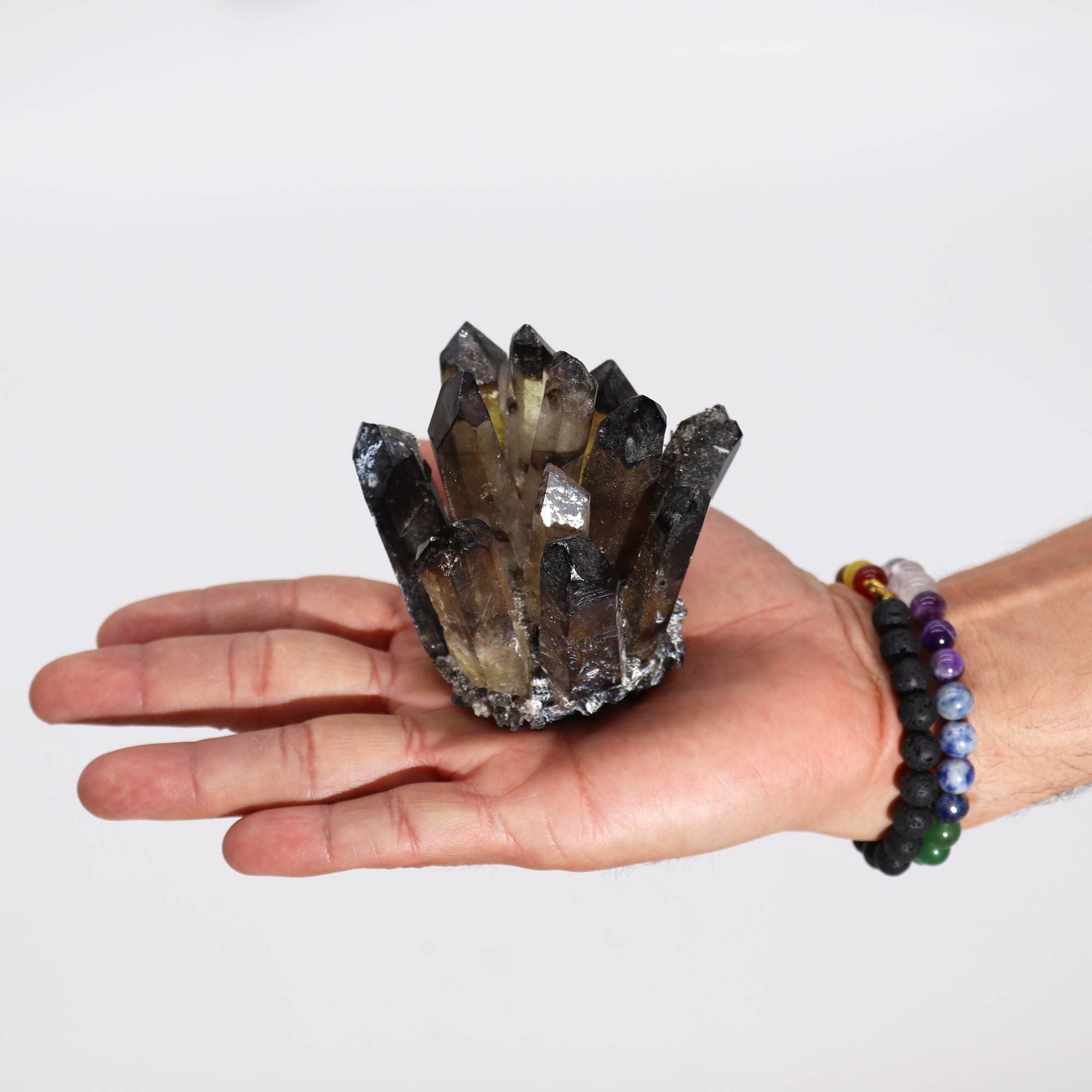 Hand holding a large crystal formation against a plain background