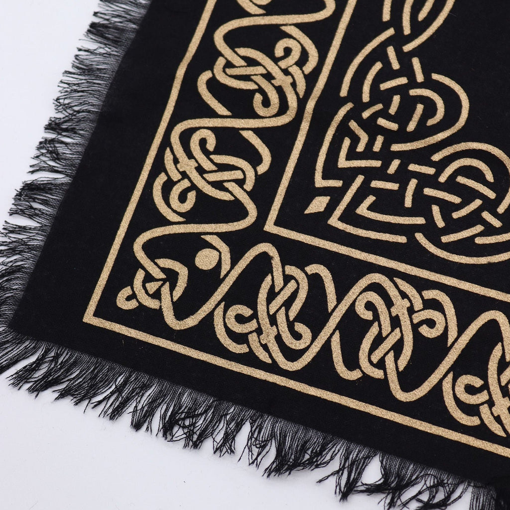Black fabric with gold intricate patterns and black fringes on a white background