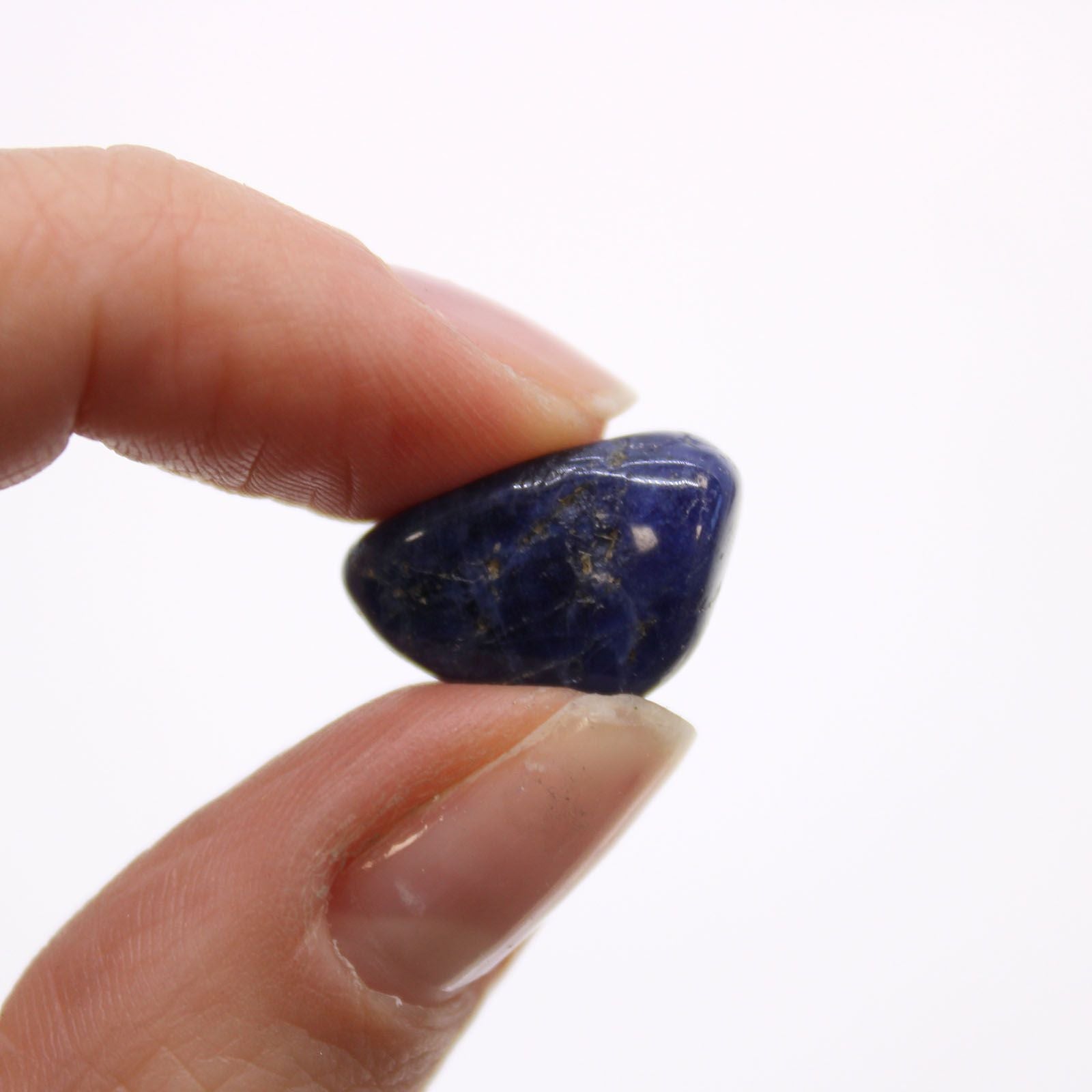 Hand holding a blue stone against a white background