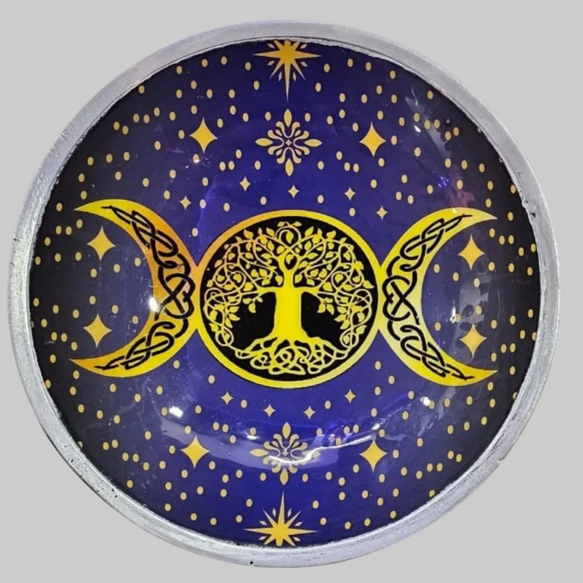 Round decorative item with yellow tree of life design and crescent moons on a blue background