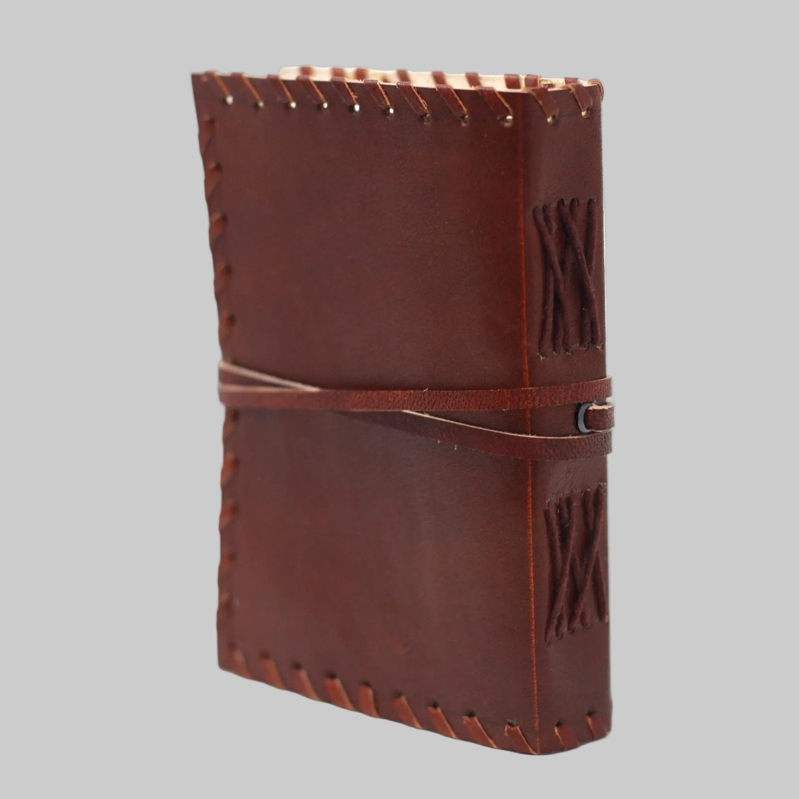 Brown leather notebook with decorative stitching on a white background