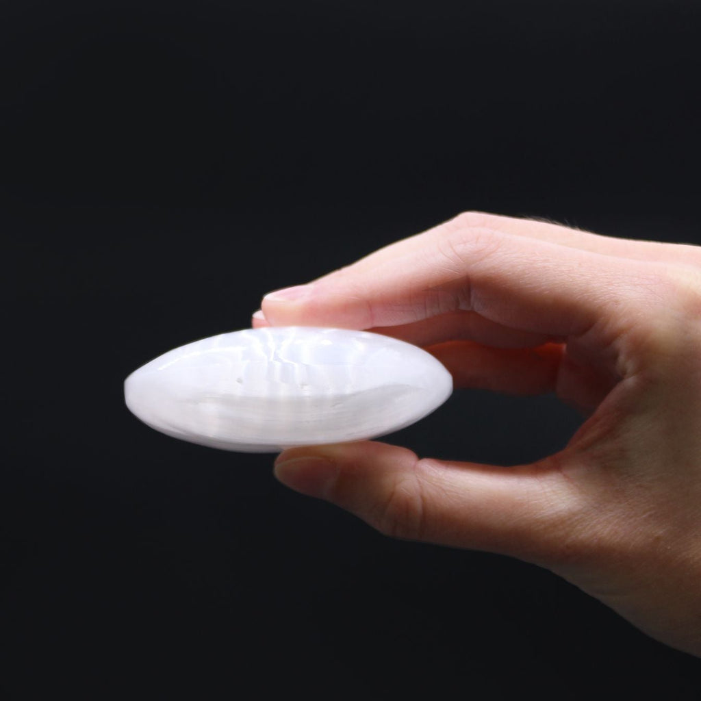 Hand holding a white silicone cupping device against a black background