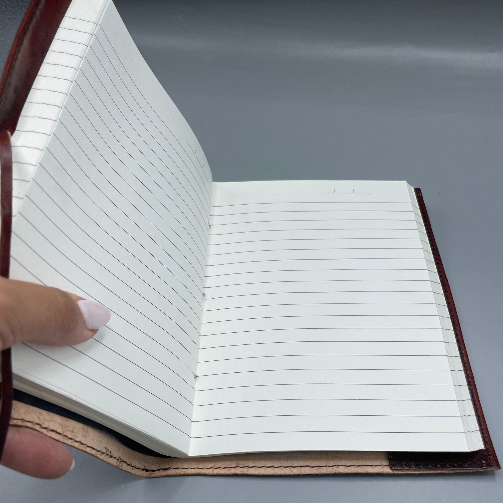 Open notebook with lined pages held by a hand on a gray background