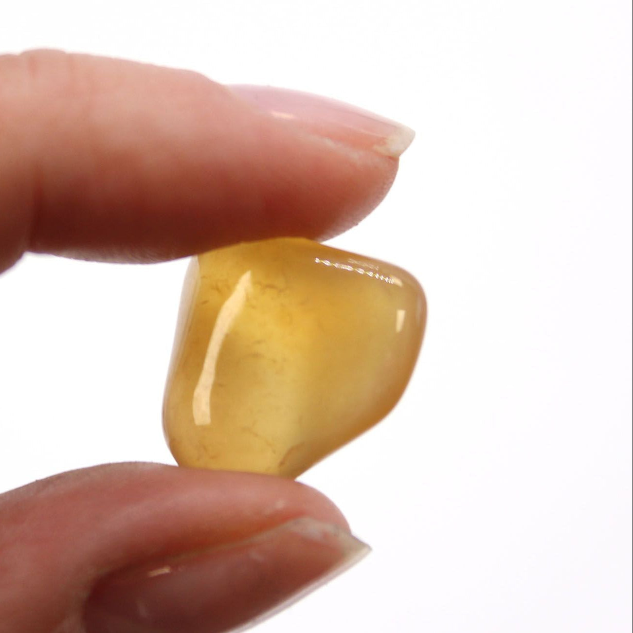 Hand holding a yellow stone against a white background