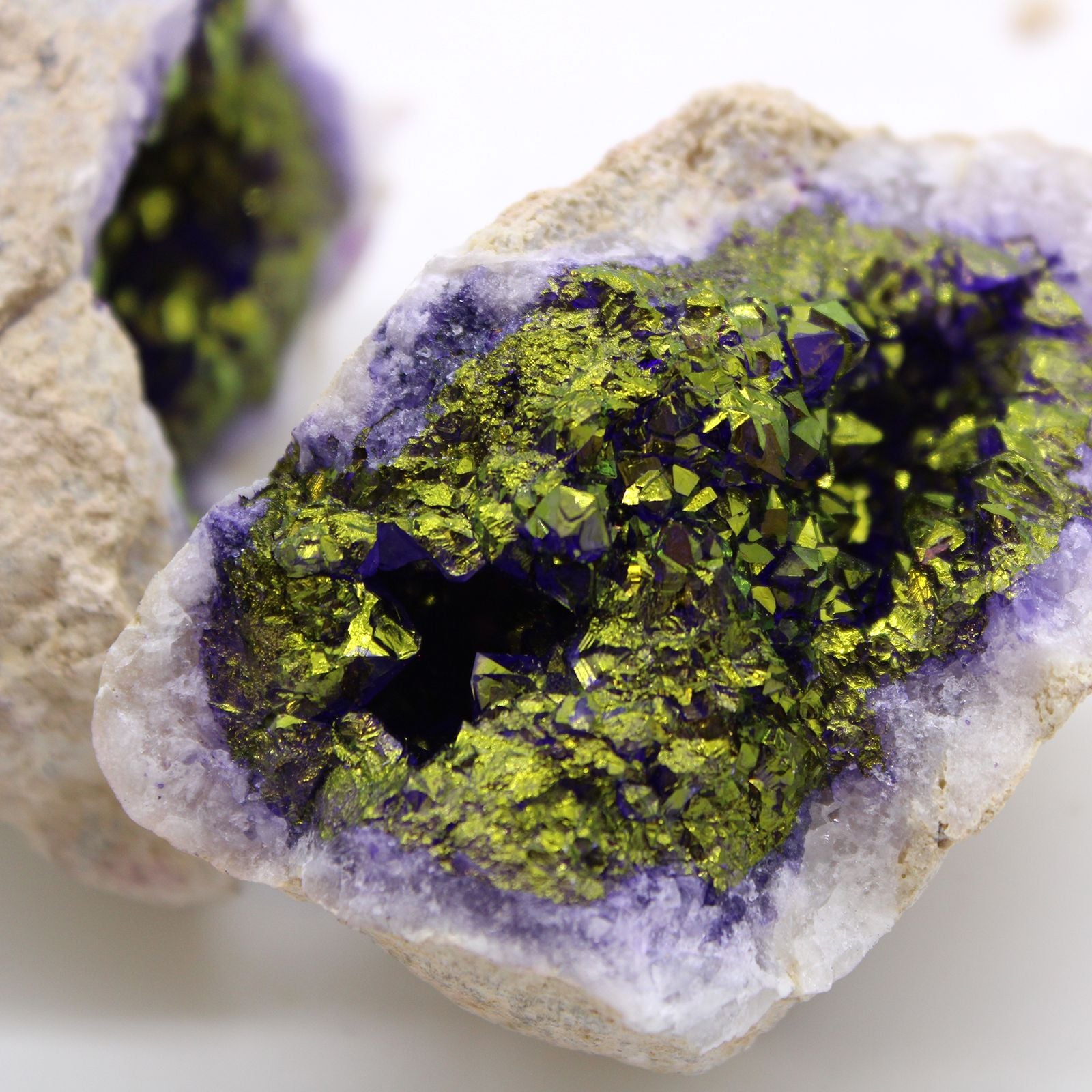 Close-up of a crystal with green and purple minerals on a light background