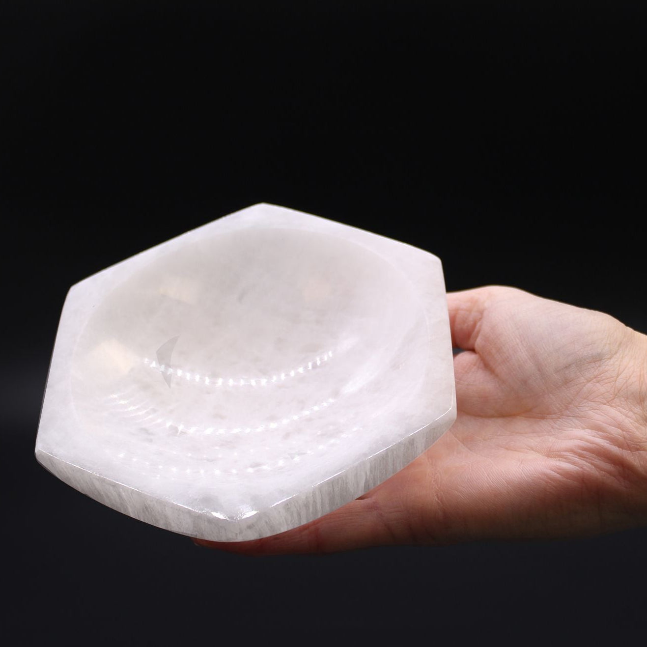Hand holding a large crystal with a black background