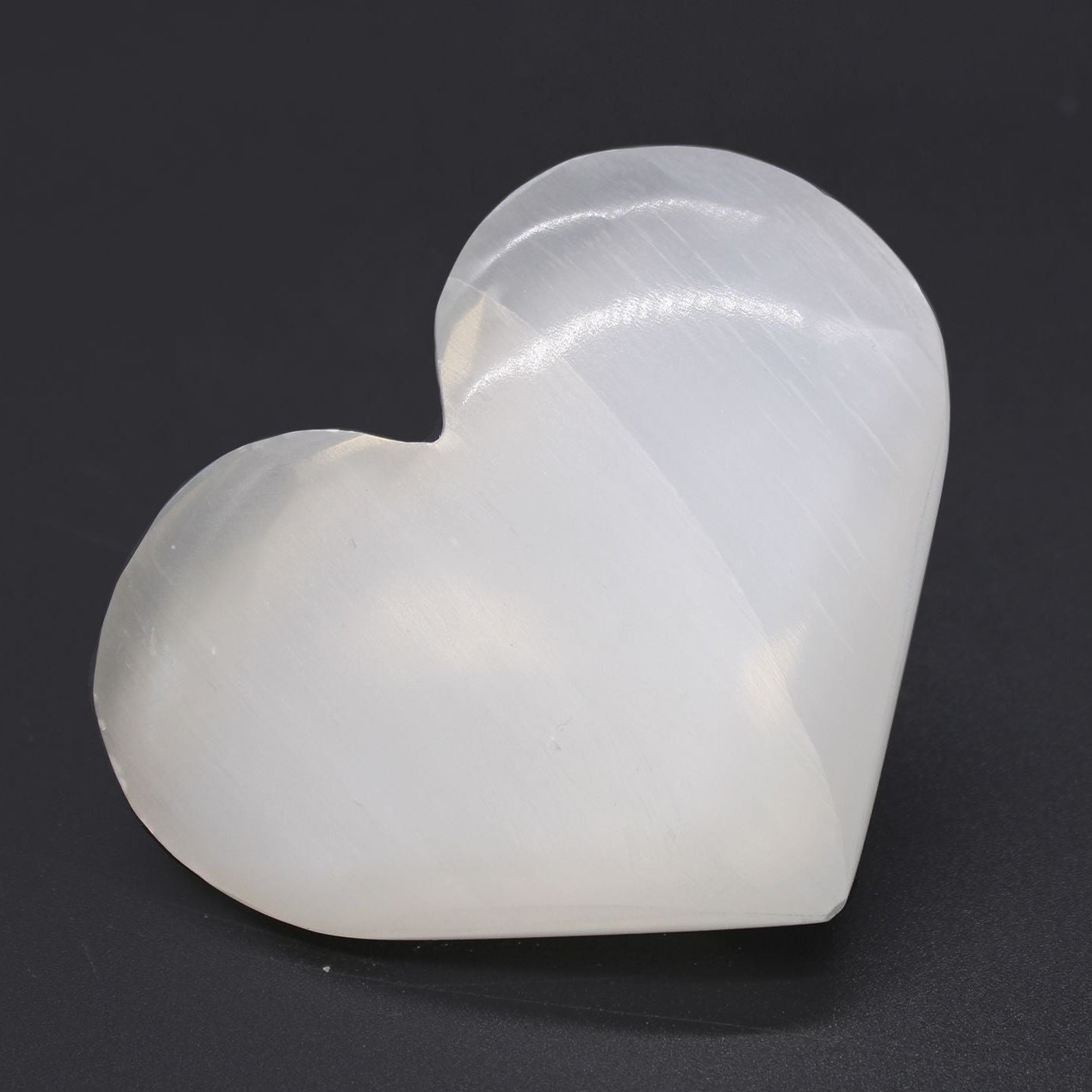 White stone sculpture of a heart on a black background