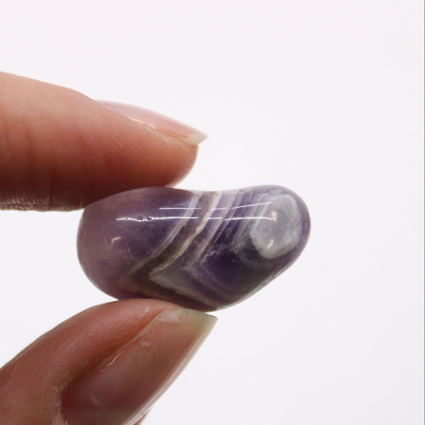 Purple and white striped stone held between two fingers against a white background