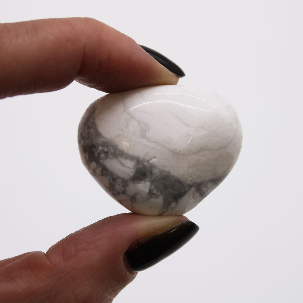 Hand holding a white and gray marbled stone against a white background