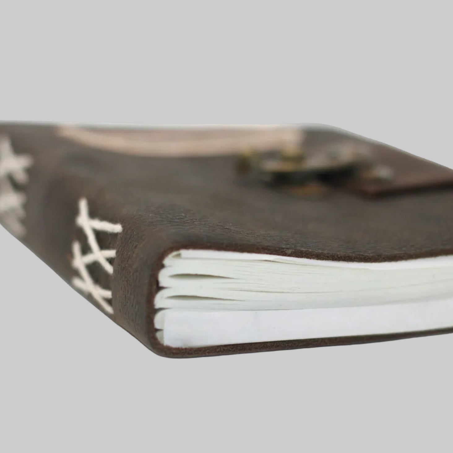 Close-up of a leather-bound notebook with white pages on a white background
